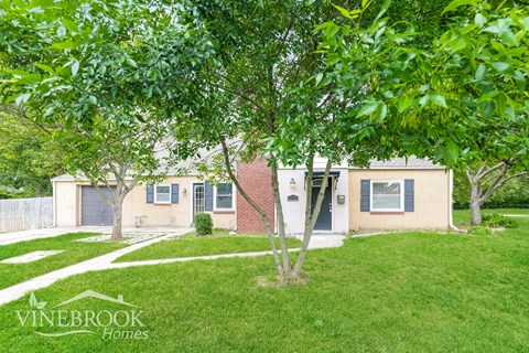 A house with a lawn and trees in front of it.