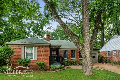 A brick house with a tree in front of it.