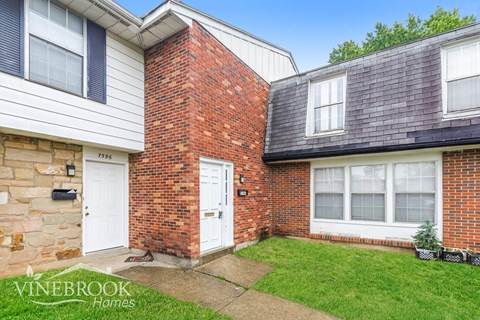 A house with a white door and a brick wall is for sale.