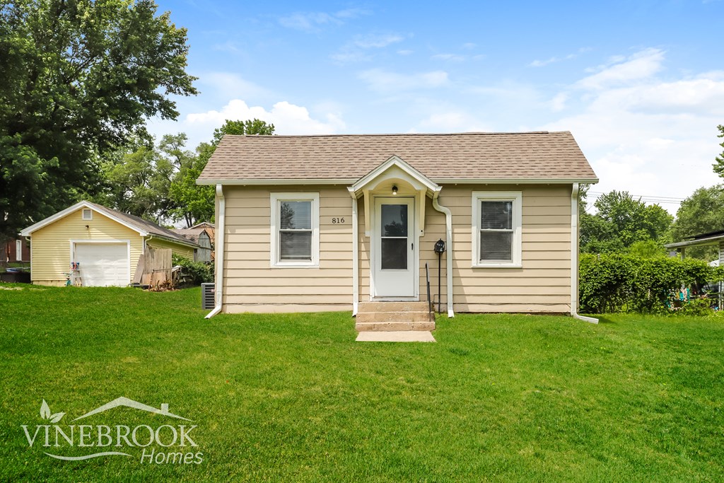 A small house with a front yard is for sale.