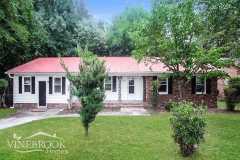 A house with a red roof and a sign that says Vinebrook Homes.
