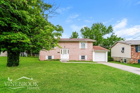 A house with a white door and a tree in front of it.