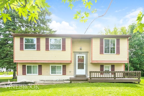 A two-story house with a front porch and a white door.