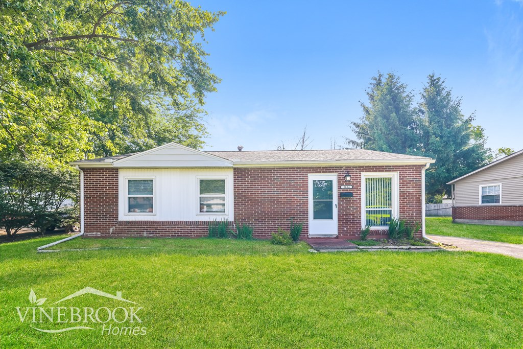 A brick house with a white door and a sign that says Vinebrook Homes.