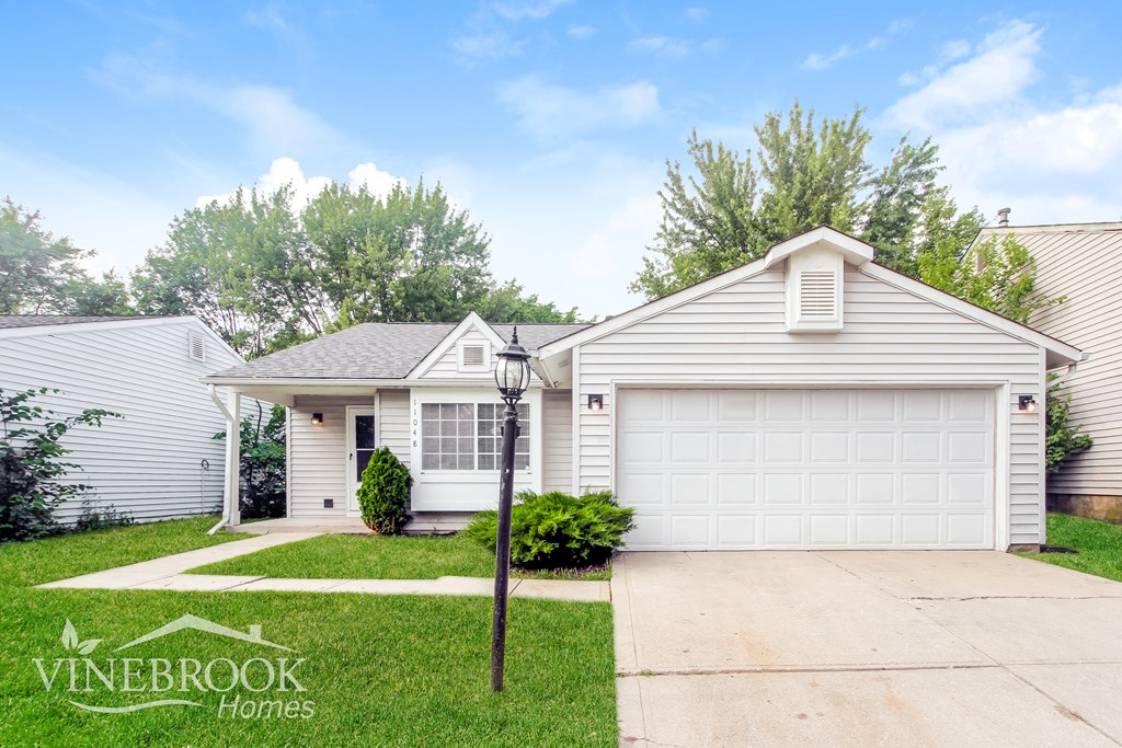 A house with a white garage door and a sign that says Vinebrook Homes.