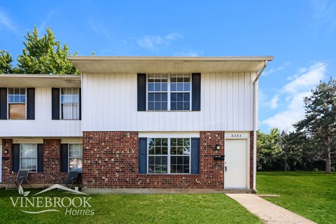 A house with a white and brick exterior is for sale.