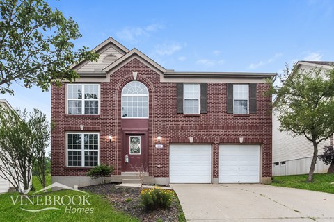 A brick house with a red door and two garage doors.
