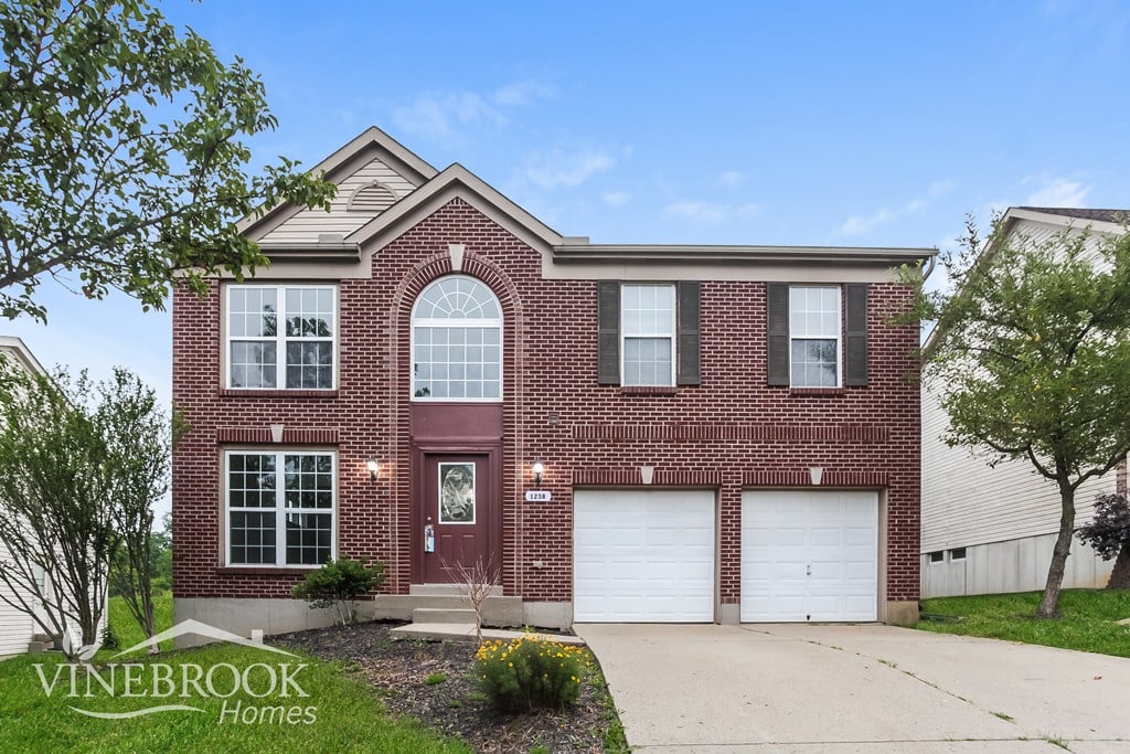A brick house with a red door and two garage doors.