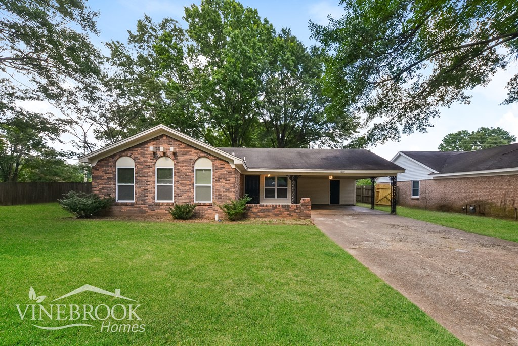 A house with a lawn in front and a tree in the background.