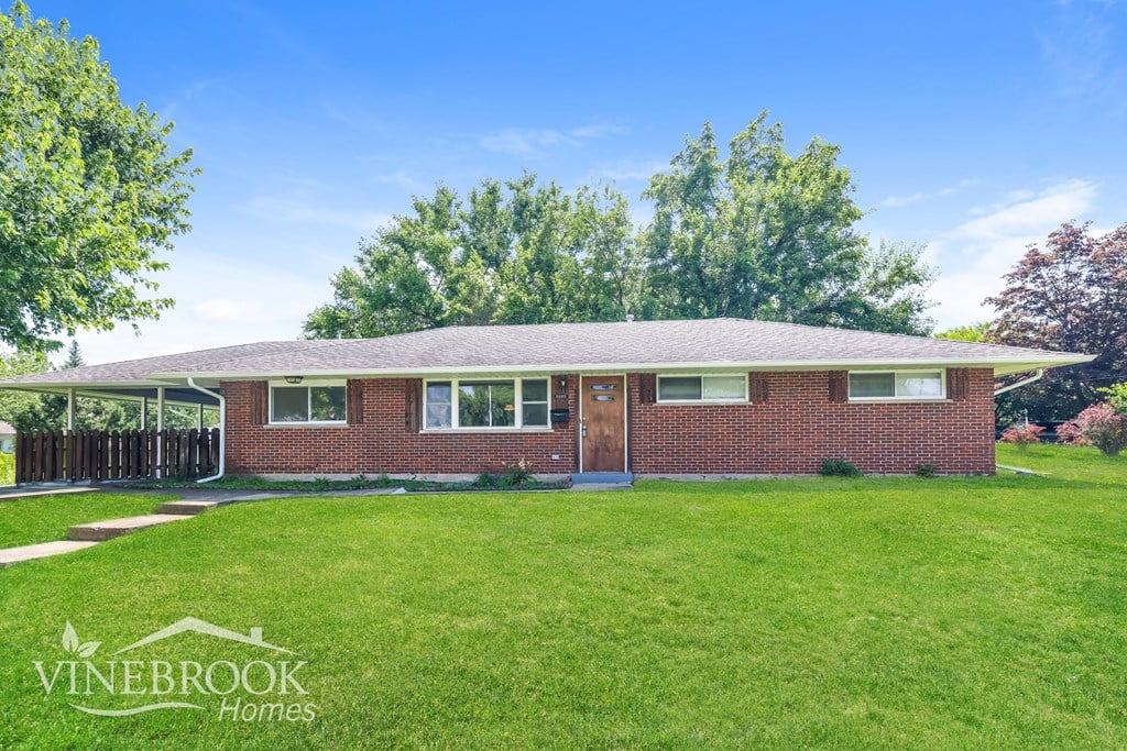 A house with a lawn in front and a sign that says Vinebrook Homes.