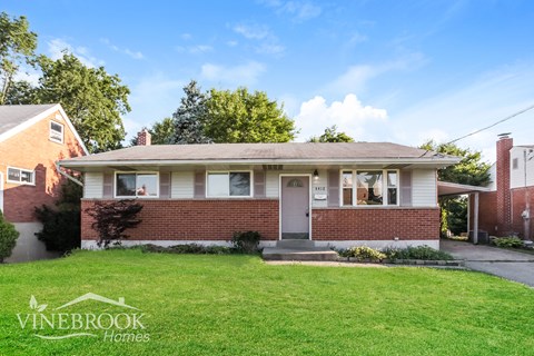 A house with a lawn in front and a sign that says Vinebrook Homes.