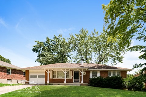 A house with a brown brick wall and a white door.