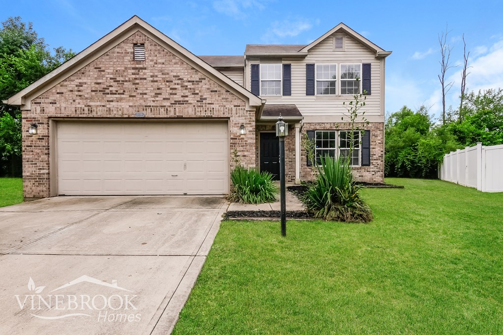 A house with a garage and a driveway in front of it.