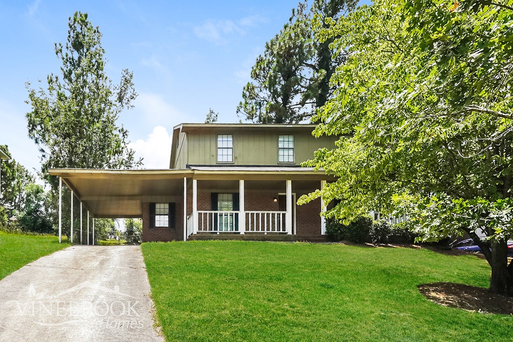 A house with a covered porch and a driveway leading to the front door.