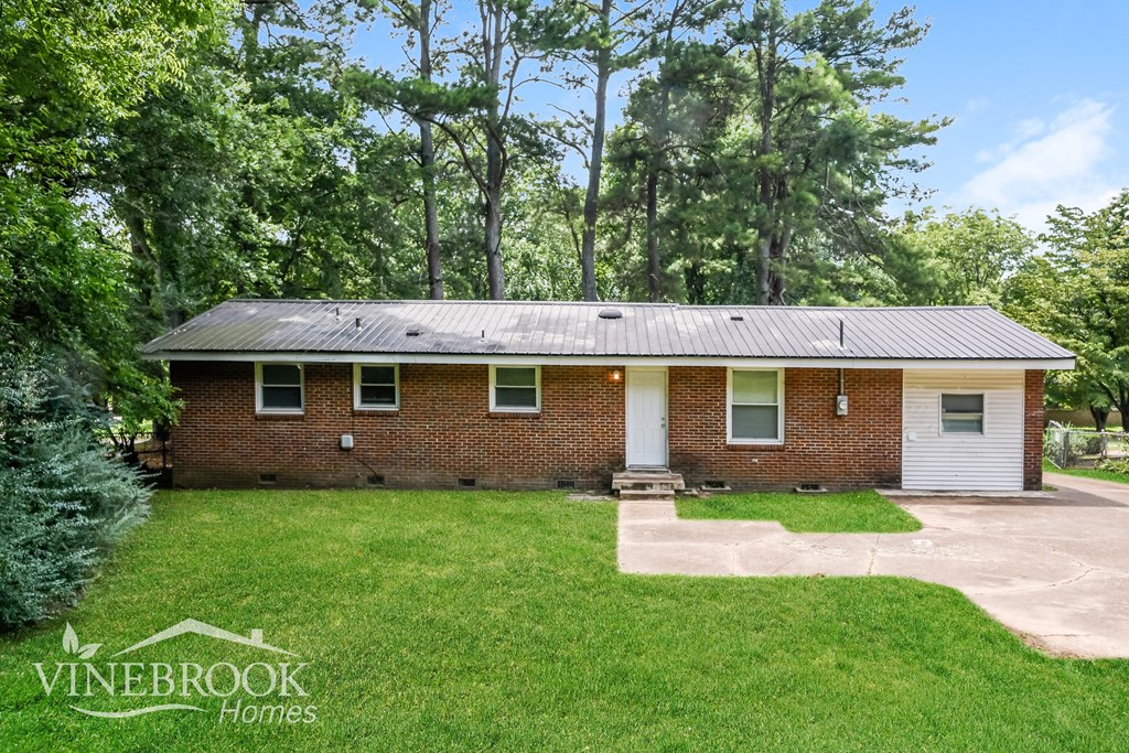 A house with a green lawn and trees in the background is for sale.
