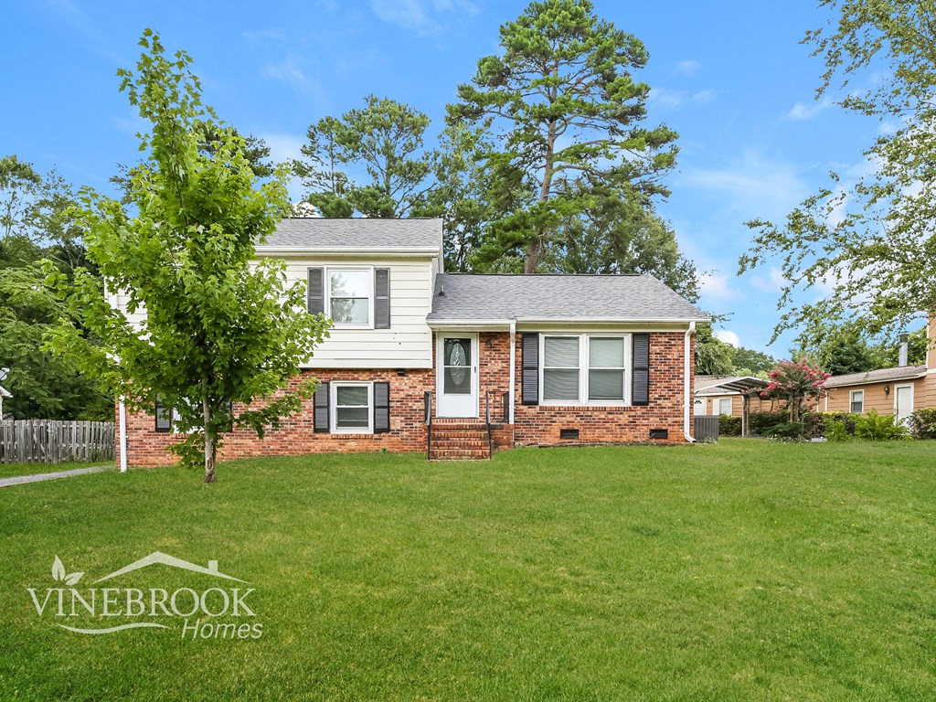 A house with a lawn in front of it and a tree to the left.
