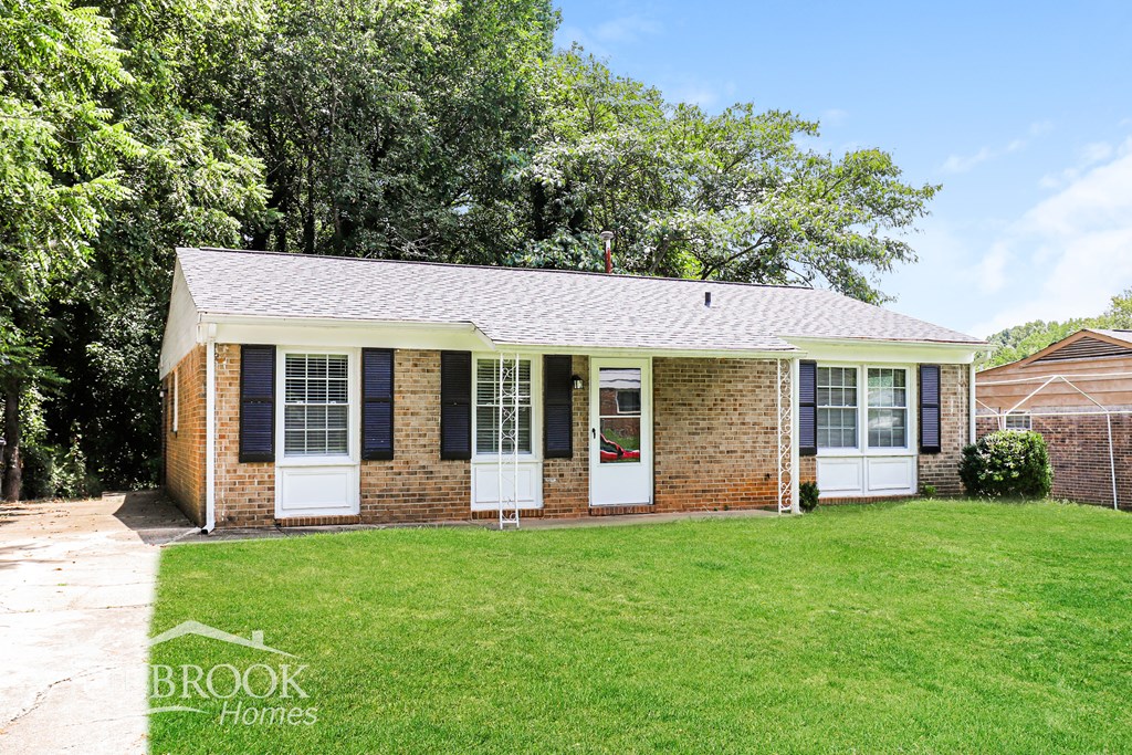 A brick house with a white door and windows is for sale.
