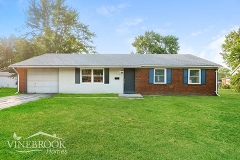 a small brick house with a lawn in front of it