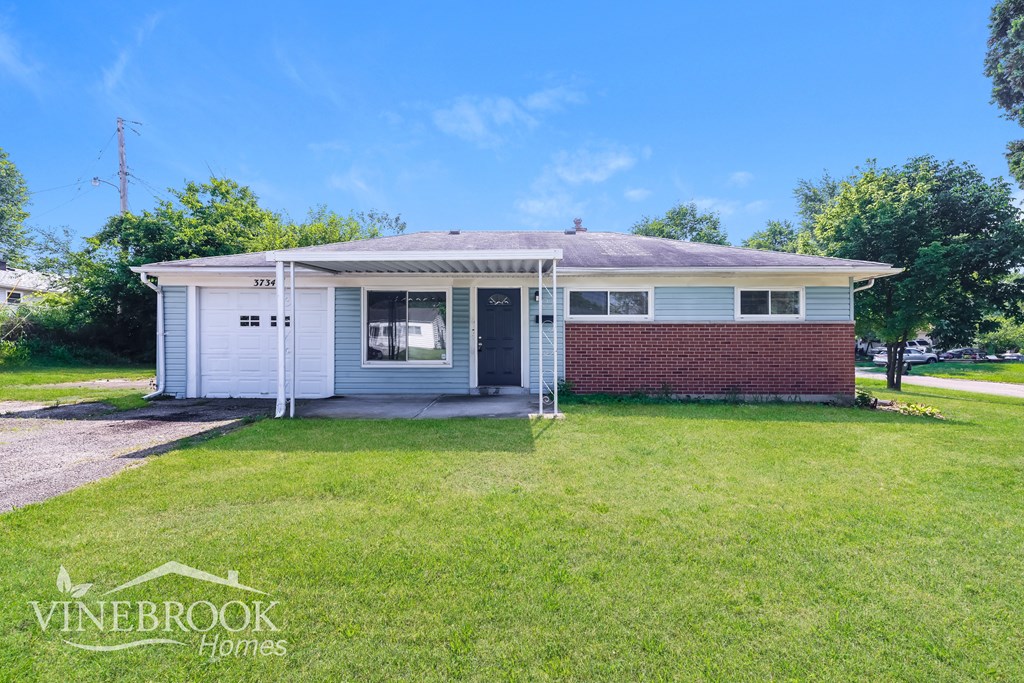 A house with a white exterior and a red brick wall is for sale.
