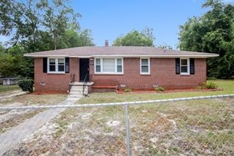a small brick house with a fence in front of it
