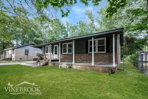 A house with a porch and a fence in front of it.