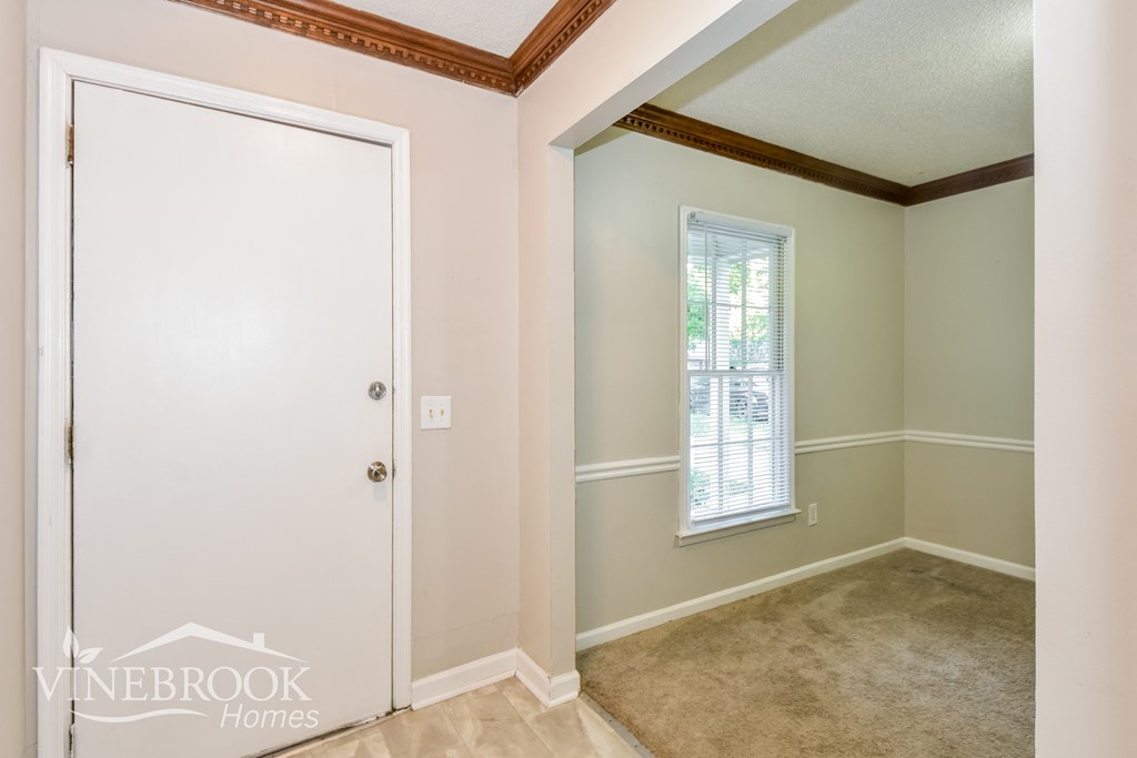 the bedroom of a home with a white door and a carpet