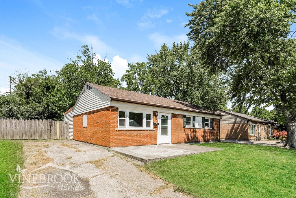 a small brick house with a yard and a driveway