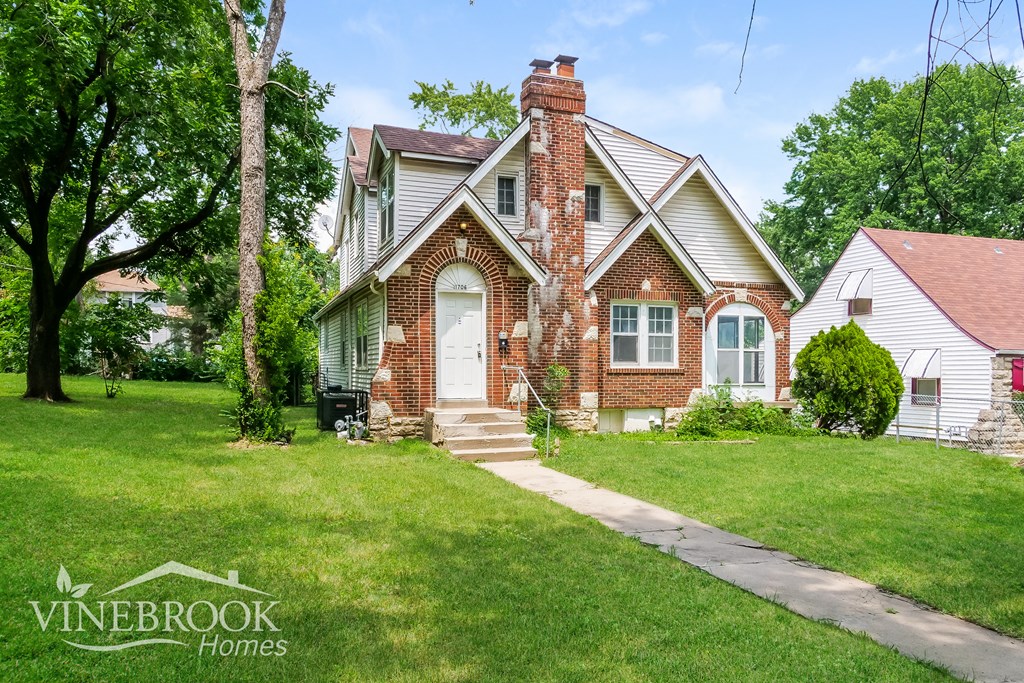 the front of a brick house with a white door and green grass