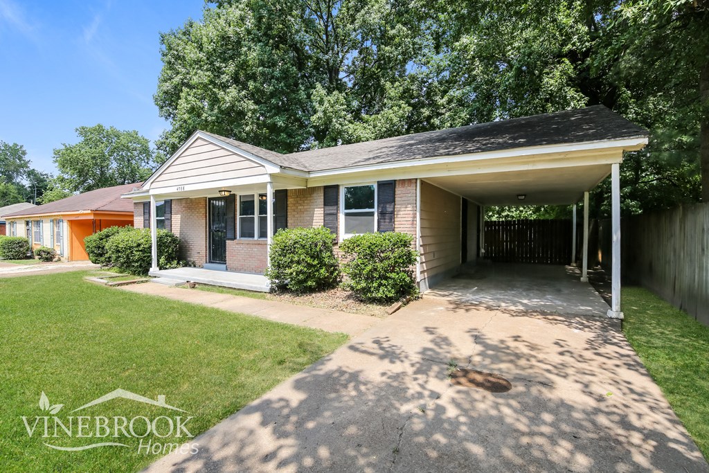 a small brick house with a driveway and a porch