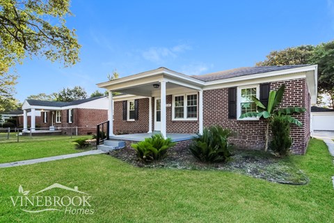 a small brick house with a lawn in front of it