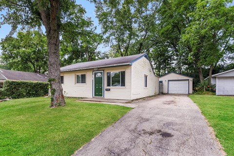 a white house with a driveway and a green door