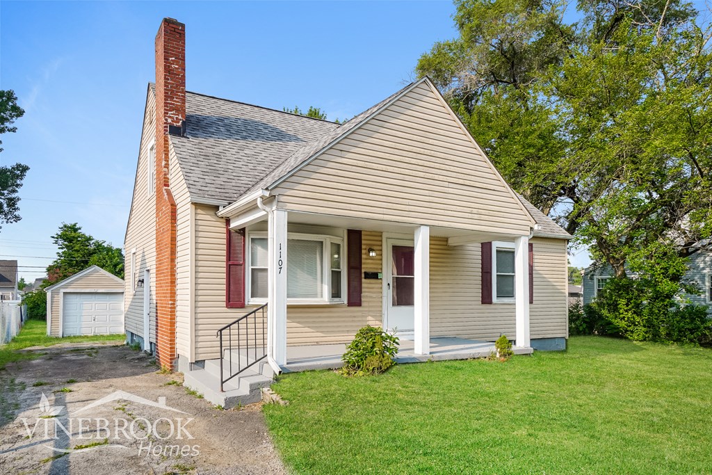 a small white house with red shutters and a lawn