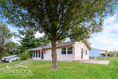 a small white house on a hill with a tree