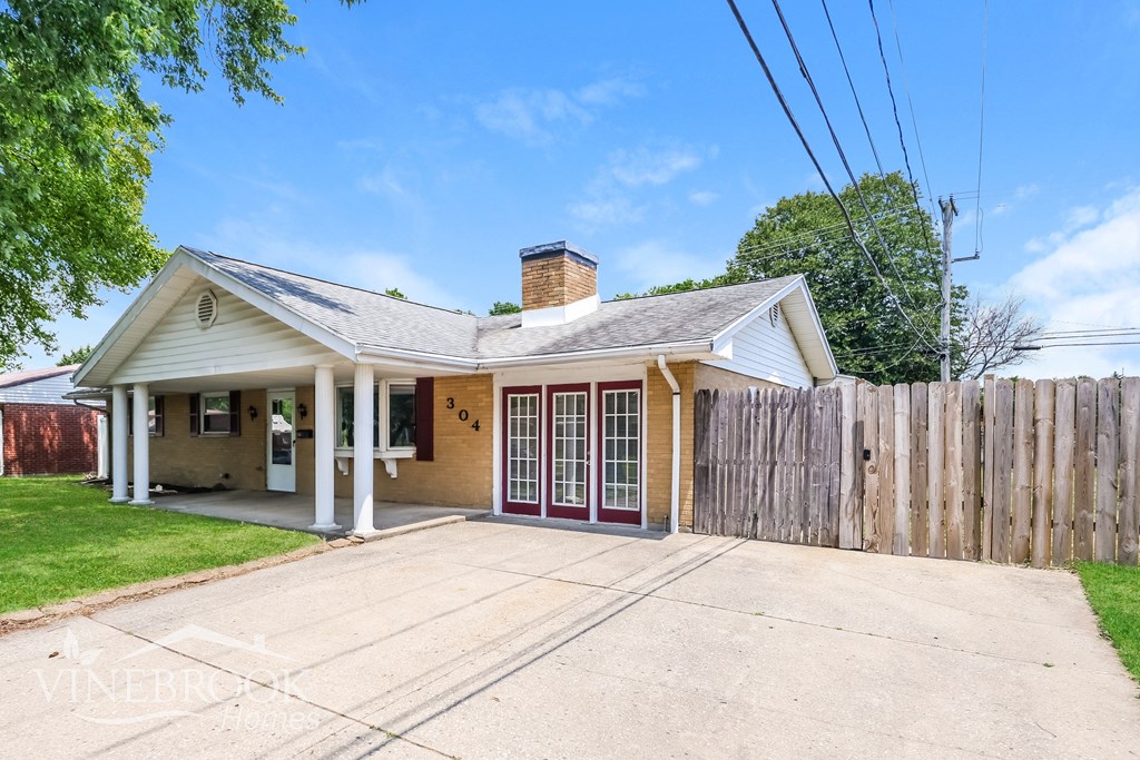 a small house with a driveway and a wooden fence
