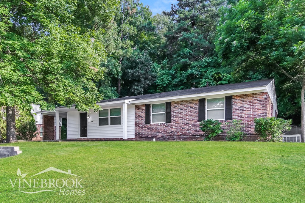 a small brick house with a lawn and trees