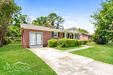 a small brick house with a sidewalk in front of it