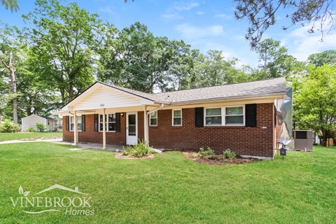 a small brick house with a lawn and trees