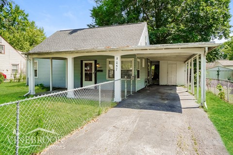 a white and green house with a driveway and a fence