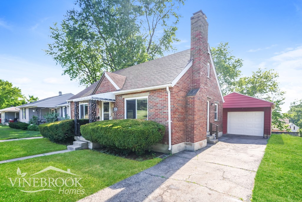 the front of a brick house with a garage and a driveway
