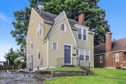 a yellow house with a blue door and a yard