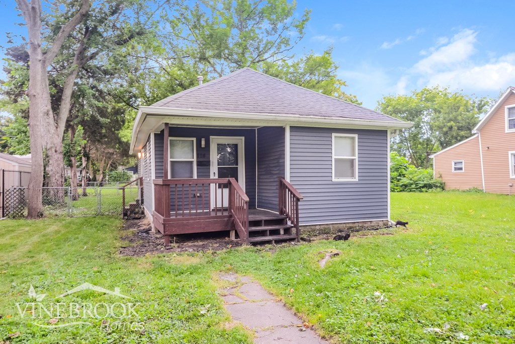 a small blue house with a wooden porch in a yard