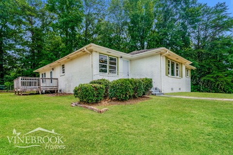 a small white house with a yard and a deck