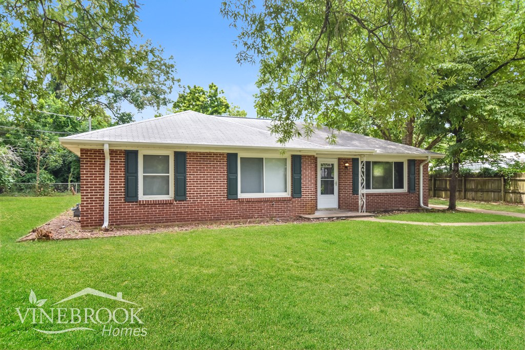 a small brick house with a lawn and trees