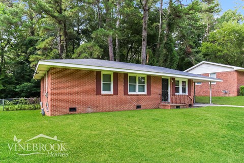 a small brick house with a green roof on a lawn
