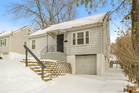 A house with a garage and a snow-covered hill in front.