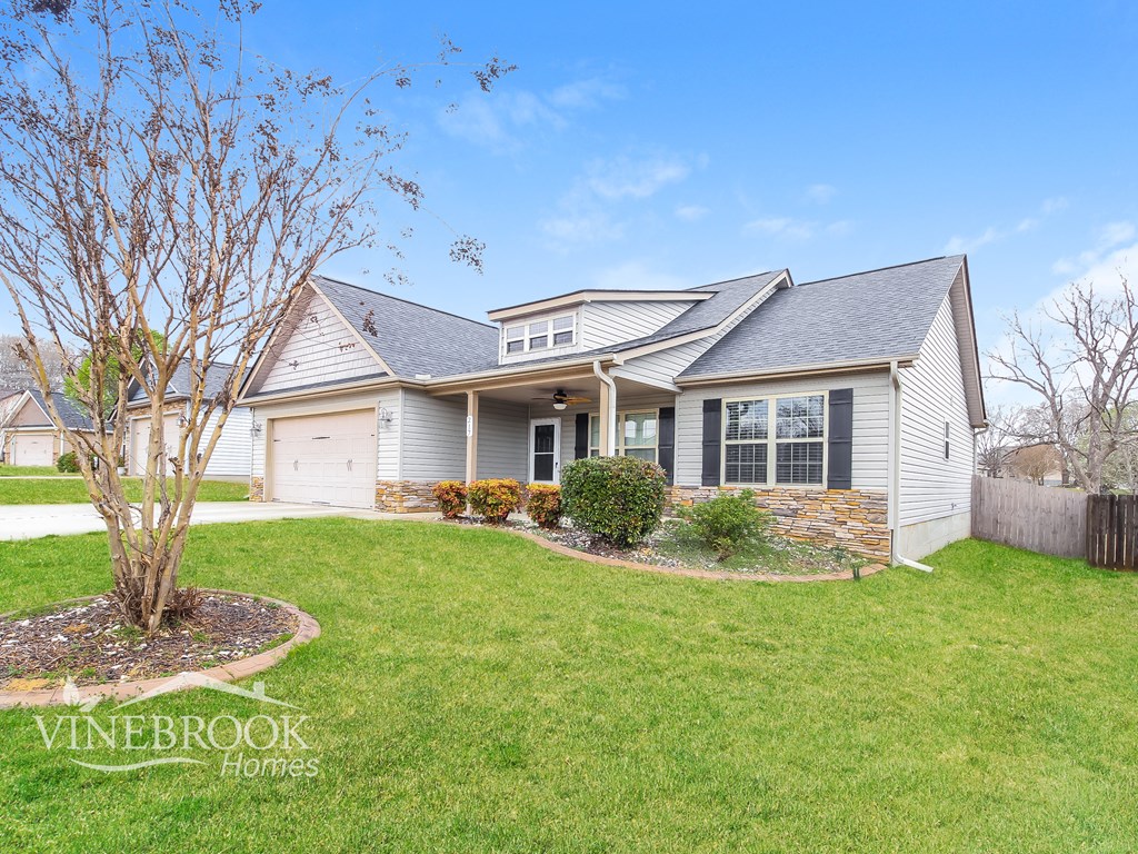 A house with a tree in front of it and the words Vinebrook Homes written on the lawn.