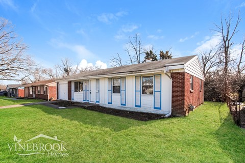 A white and blue house with the words Vinebrook Homes written on the bottom left.
