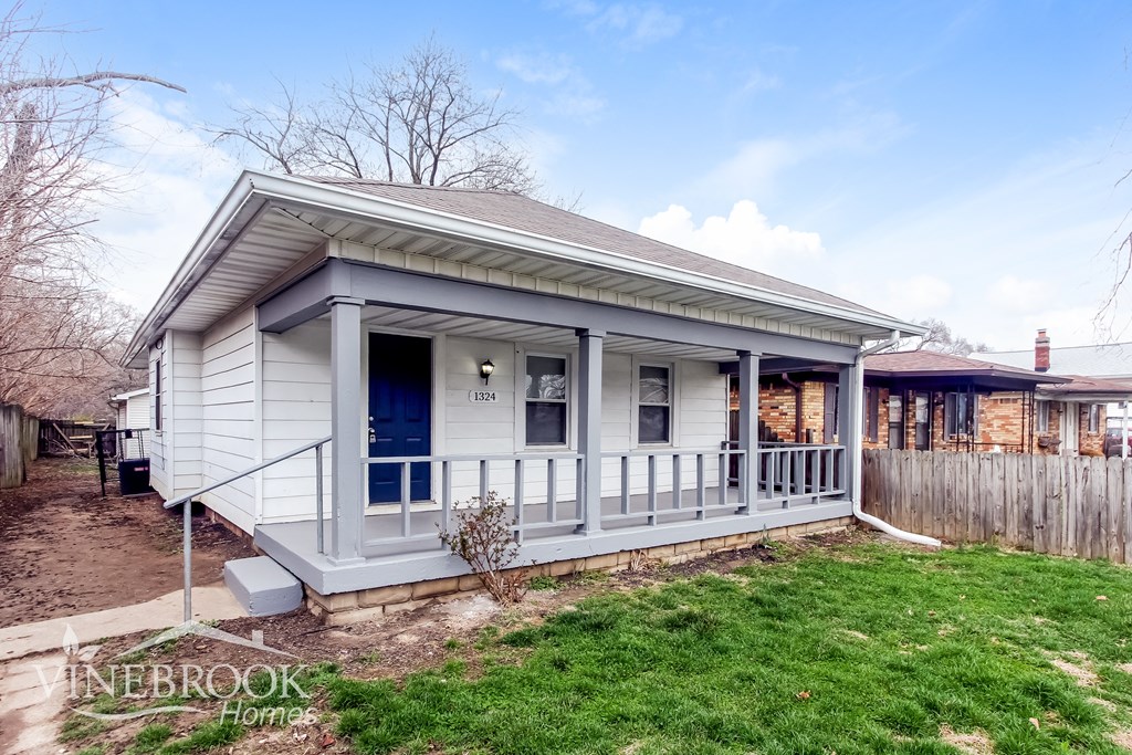 A house with a porch and a blue door is for sale.