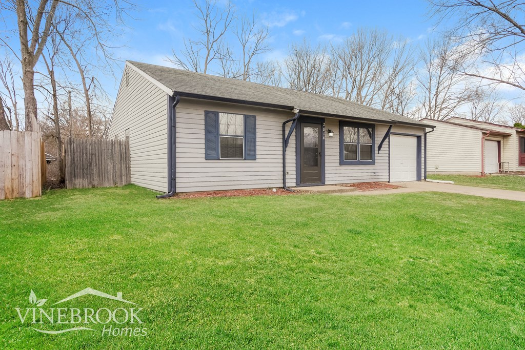 A house with a fence and a lawn in front of it.