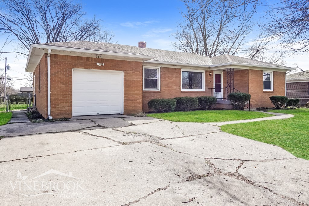 A brick house with a white garage door and a driveway in front.